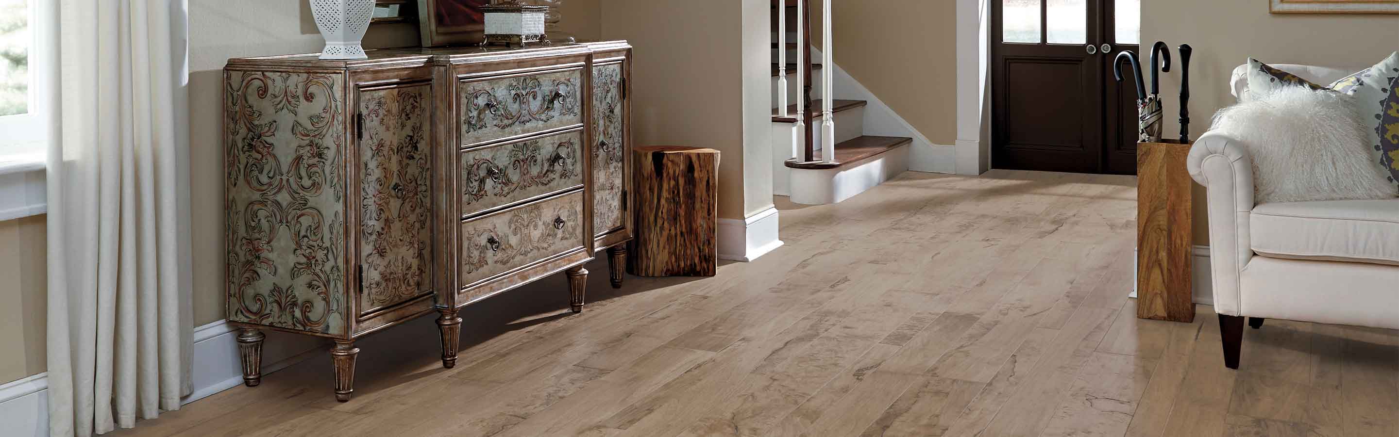  distressed hardwood floors in contemporary entryway into living room with white couch, vintage sideboard and neutral colorways
